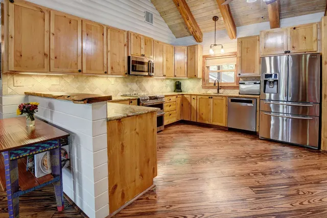 a kitchen with stainless steel appliances granite countertop a refrigerator a stove top oven a sink and dishwasher