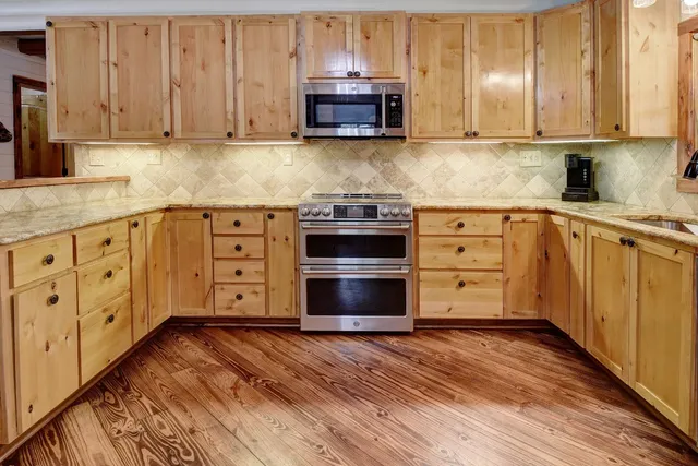a kitchen with cabinets appliances and a wooden floor