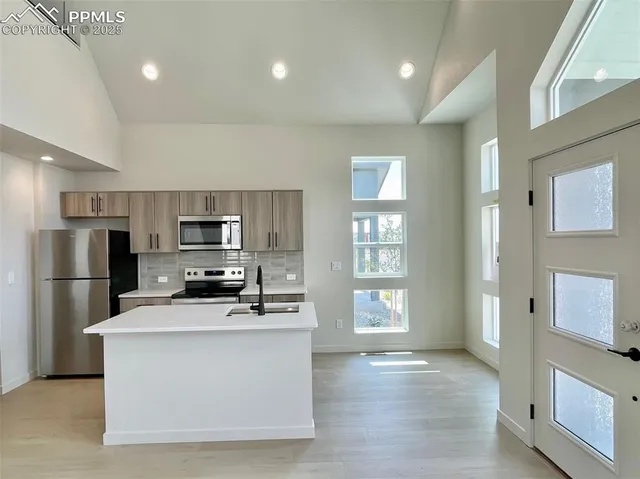 a kitchen with stainless steel appliances a refrigerator a stove a sink a microwave a window and white cabinets