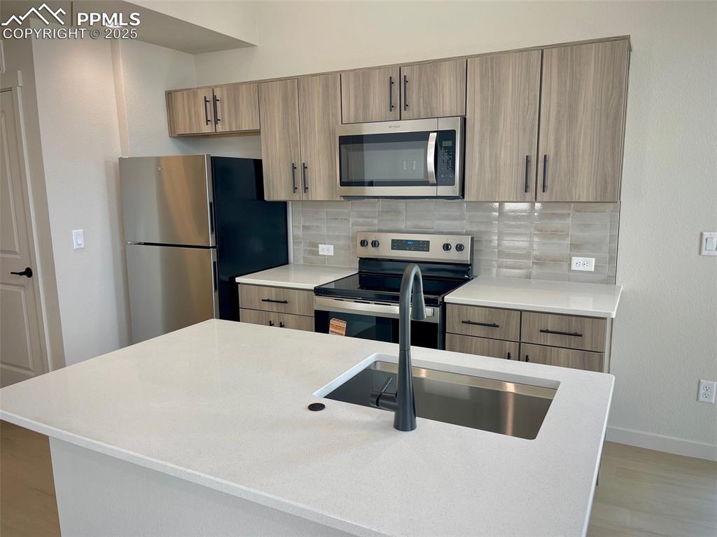 3535 Greenways Main Boulevard Colorado Springs, CO 80922 - Photo 3 of 22 a kitchen with stainless steel appliances a refrigerator a stove a microwave and cabinets