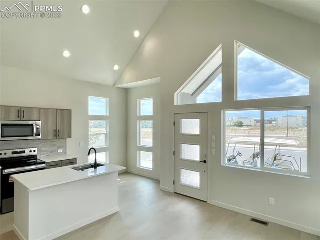 a large kitchen with stainless steel appliances a large window a sink and a counter top space