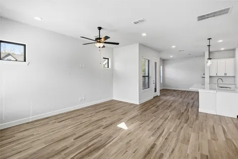 a view of empty room with wooden floor and fan