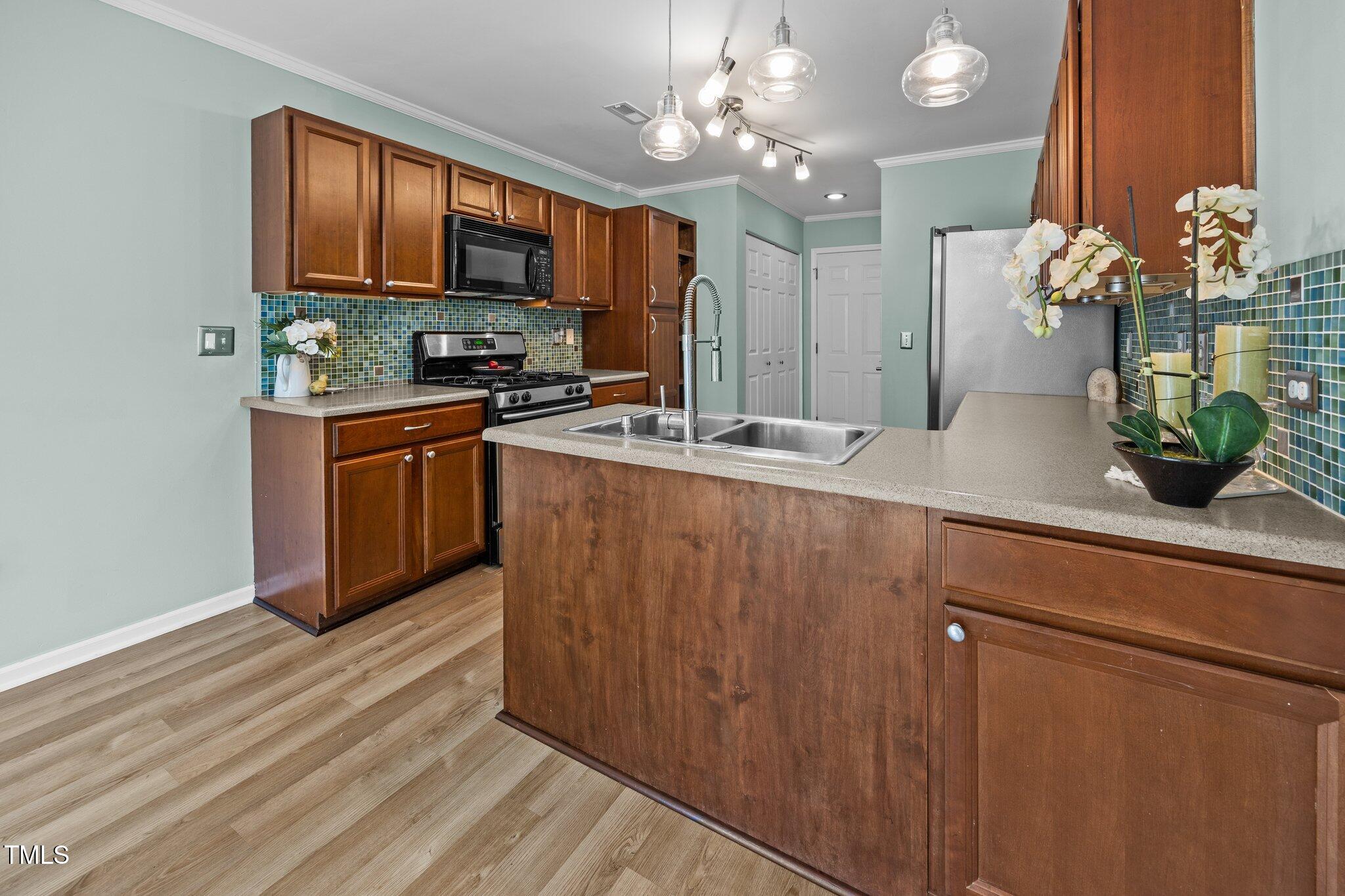 5561 Roan Mountain Place Raleigh, NC 27613 - Photo 3 of 20 a kitchen with stainless steel appliances granite countertop a sink a stove and a wooden cabinets