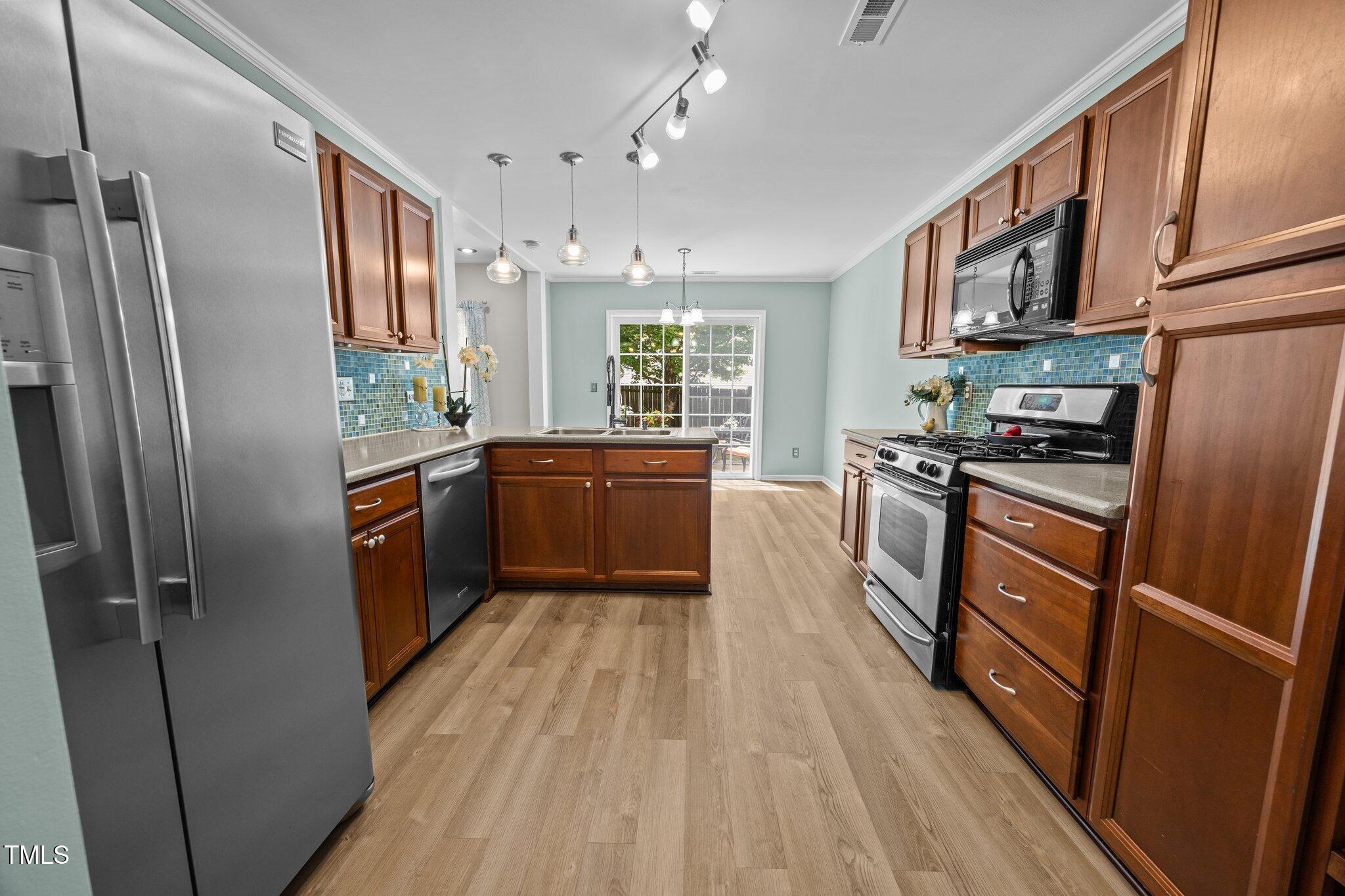 5561 Roan Mountain Place Raleigh, NC 27613 - Photo 5 of 20 a kitchen with stainless steel appliances granite countertop refrigerator a sink dishwasher a stove top oven a refrigerator with wooden floor