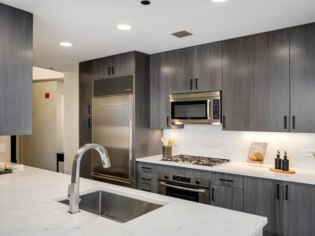 a kitchen with stainless steel appliances kitchen island granite countertop a refrigerator and a stove top oven