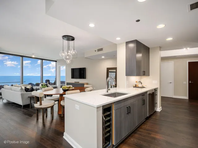 a large kitchen with stainless steel appliances a stove a sink dishwasher and a dining table with wooden floor