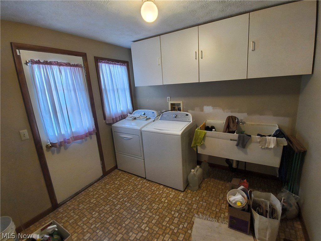 2672 Crackel Road Aurora, OH 44202 - Photo 15 of 38 Laundry room featuring washer and dryer, cabinet space, and a textured ceiling