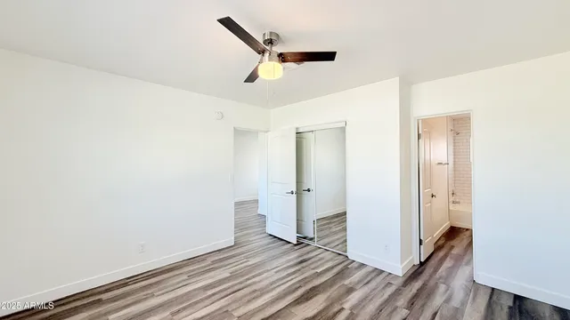 an empty room with wooden floor and a ceiling fan