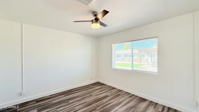 a view of empty room with wooden floor and fan