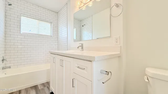 a bathroom with a granite countertop sink a mirror and a bathtub