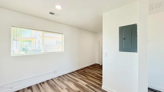 a view of an empty room with wooden floor and a window