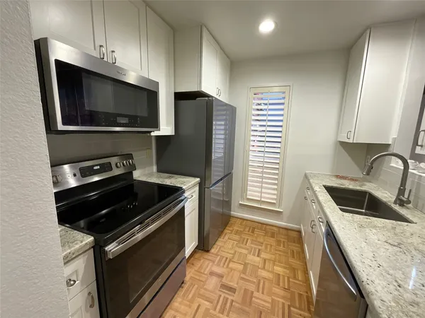 a kitchen with granite countertop a sink and steel appliances