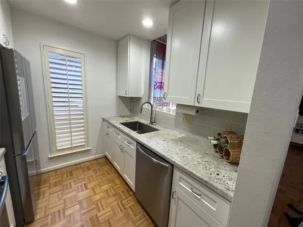 a kitchen with granite countertop stainless steel appliances a sink a counter space and cabinets