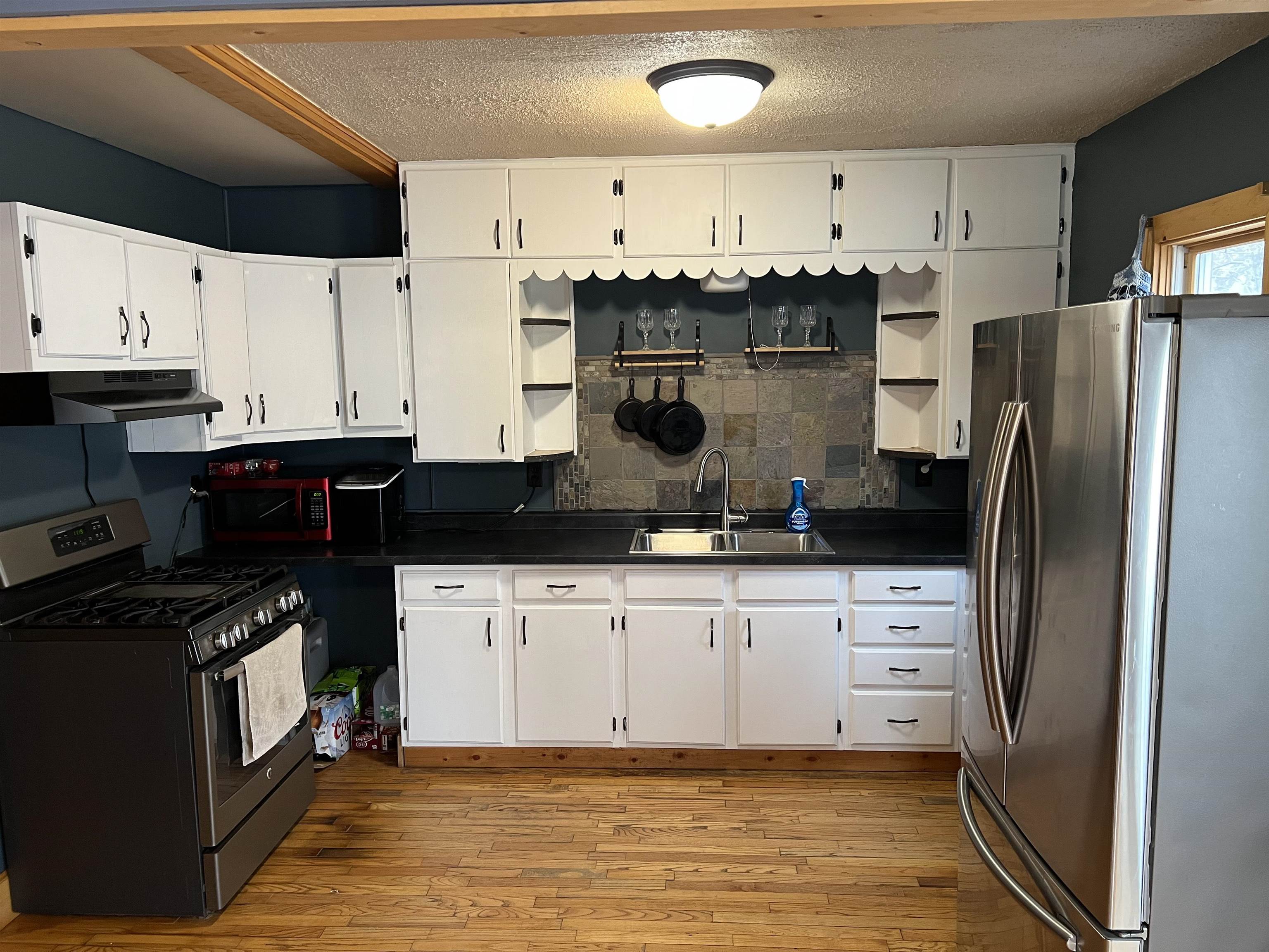 616 Cranston Road Beloit, WI 53511 - Photo 8 of 21 a kitchen with stainless steel appliances kitchen island granite countertop a refrigerator a stove a sink dishwasher and white cabinets with wooden floor