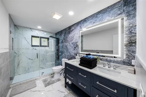 a bathroom with a double vanity sink toilet and shower