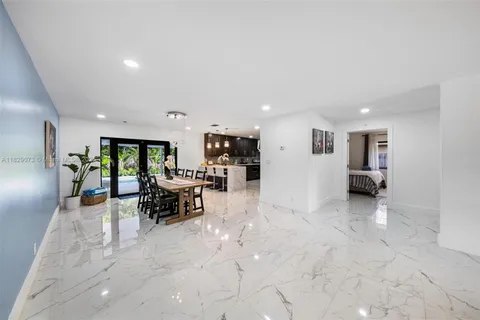 a view of a living room kitchen with stainless steel appliances refrigerator stove microwave and furniture