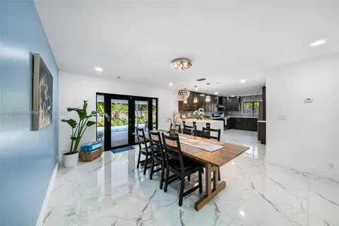 a dining room with furniture a potted plant and a kitchen view