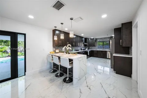 a kitchen with stainless steel appliances kitchen island granite countertop a refrigerator and a sink
