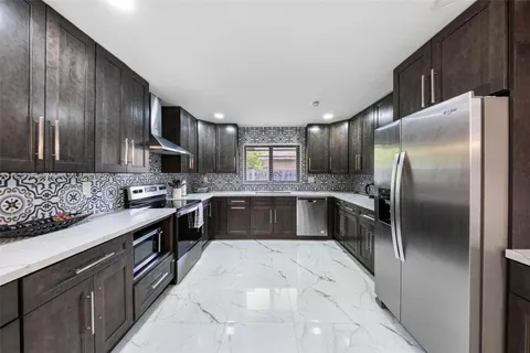 a kitchen with stainless steel appliances granite countertop a sink a stove a refrigerator and cabinets