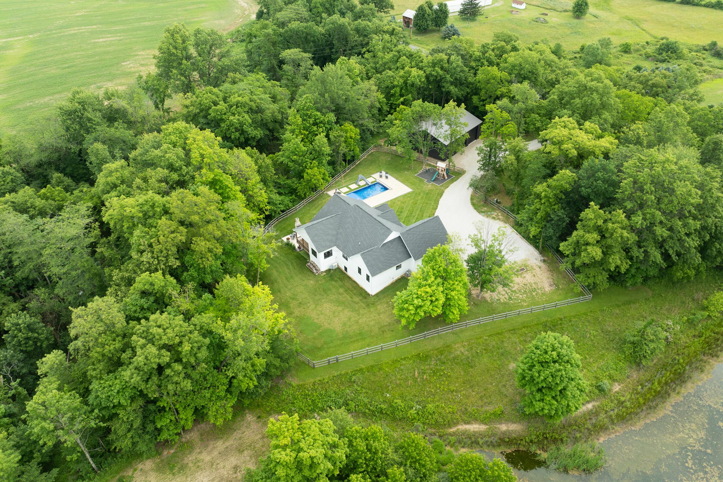 Aerial view of the 4734 SqFt home and property amid mature trees in a peaceful rural setting.