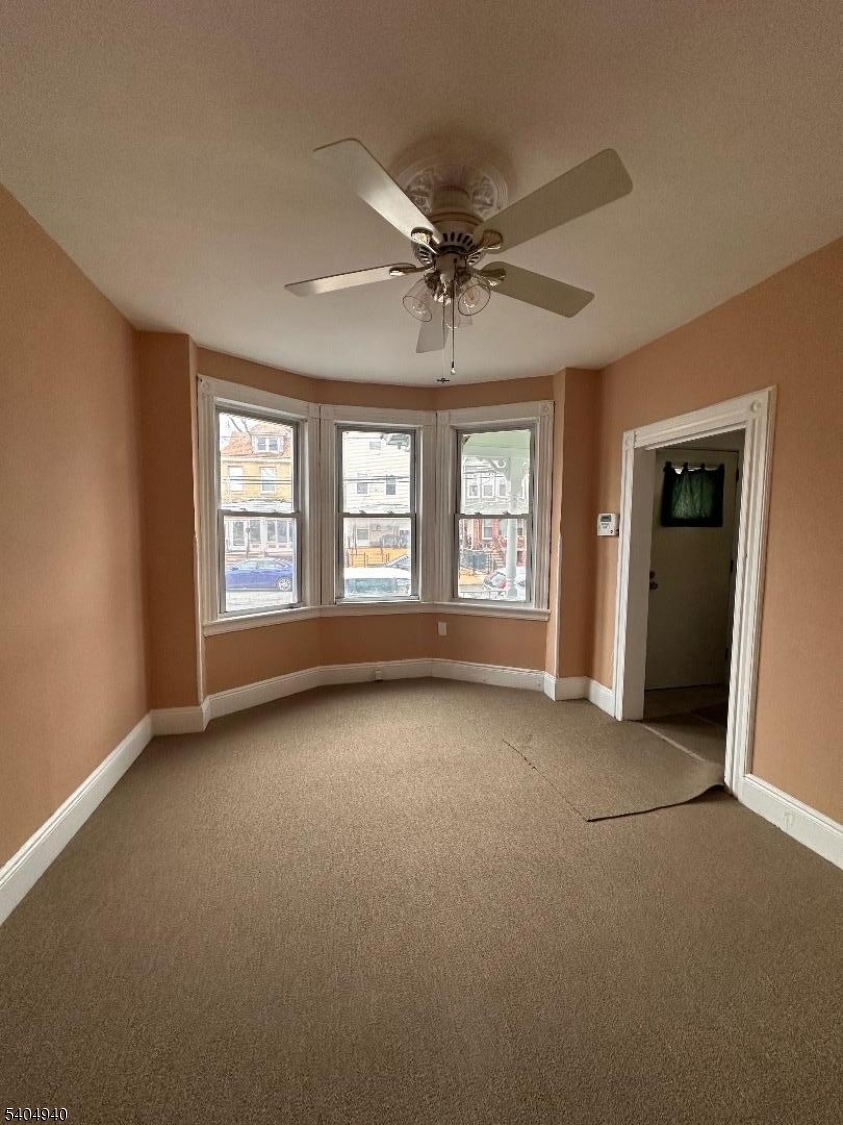 956 Lafayette Street Elizabeth, NJ 07201 - Photo 4 of 20 an empty room with windows and ceiling fan