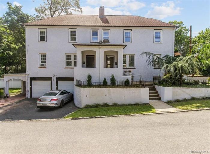 View of front facade with driveway, stairway, an attached garage, and a chimney