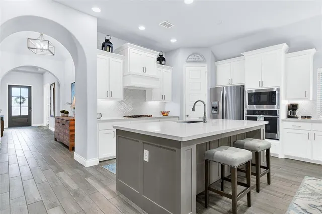 a kitchen with stainless steel appliances granite countertop a stove refrigerator and cabinets