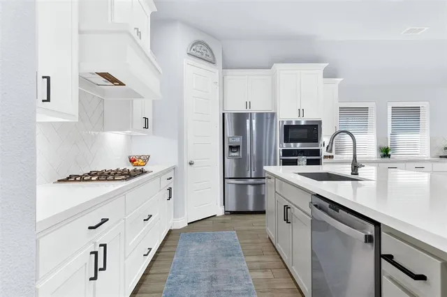 a kitchen with white cabinets and appliances