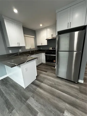 a kitchen with stainless steel appliances granite countertop a refrigerator a stove a sink and a microwave