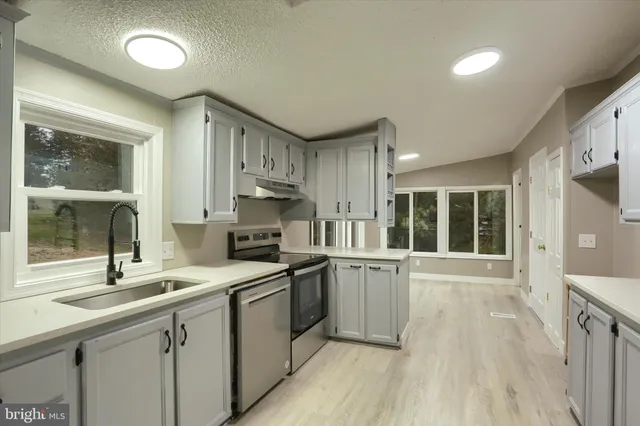 a kitchen with a sink appliances cabinets and a large window