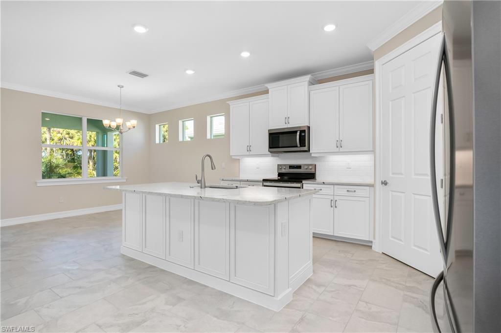 331 Tamarindo Lane Naples, FL 34114 - Photo 11 of 24 a kitchen with white cabinets and a refrigerator