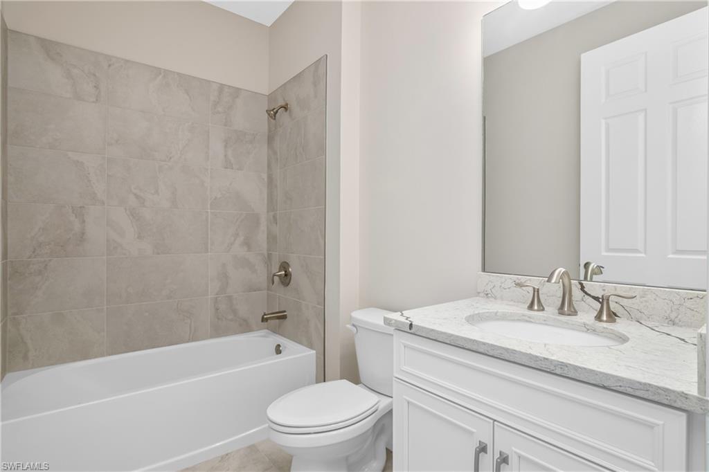 331 Tamarindo Lane Naples, FL 34114 - Photo 19 of 24 a bathroom with a granite countertop bathtub shower sink vanity mirror and toilet