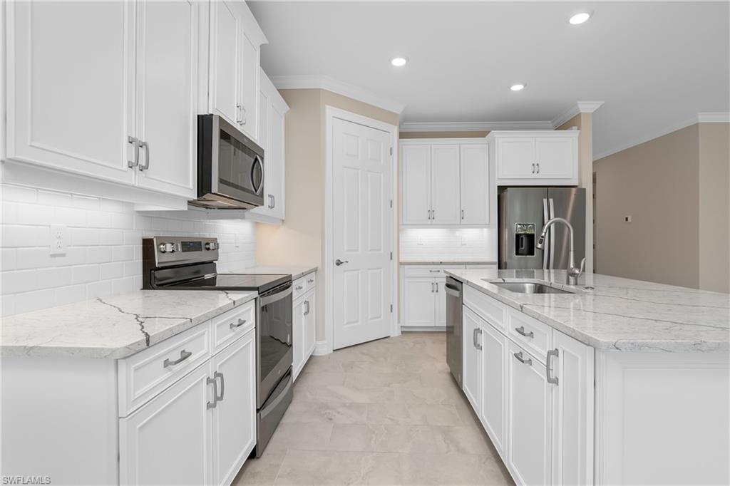 331 Tamarindo Lane Naples, FL 34114 - Photo 10 of 24 a kitchen with white cabinets sink and stove