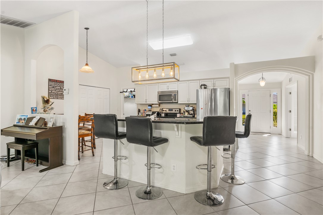 3660 2nd Street Southwest Vero Beach, FL 32968 - Photo 11 of 36 a kitchen with stainless steel appliances kitchen island granite countertop a table and chairs in it
