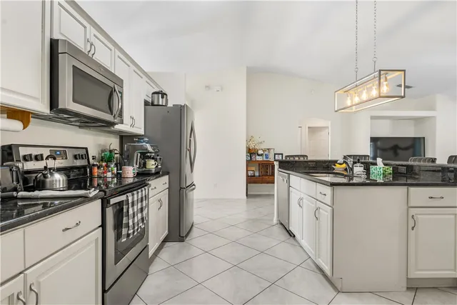 a kitchen with stainless steel appliances granite countertop a stove top oven a sink dishwasher and a refrigerator with wooden cabinets