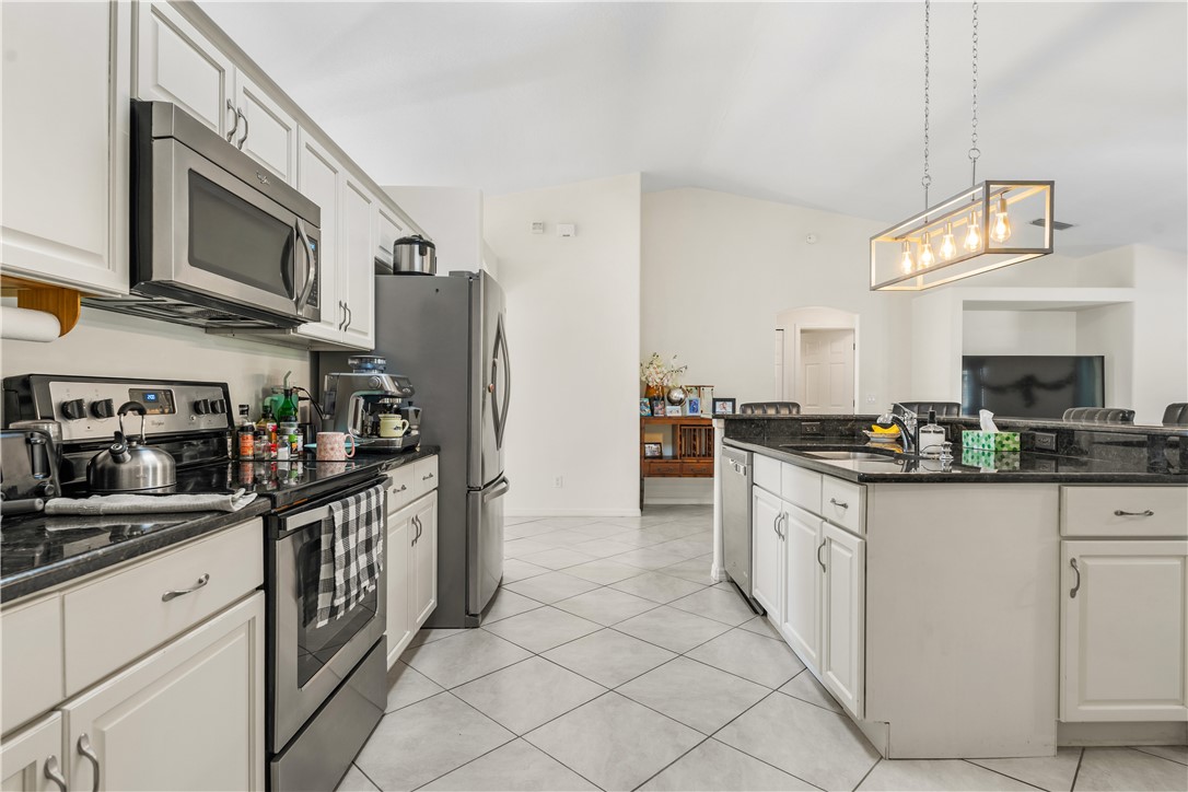 3660 2nd Street Southwest Vero Beach, FL 32968 - Photo 12 of 36 a kitchen with stainless steel appliances granite countertop a stove top oven a sink dishwasher and a refrigerator with wooden cabinets