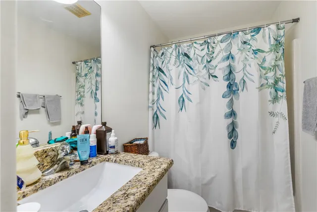 a bathroom with a granite countertop sink a toilet and a shower curtain
