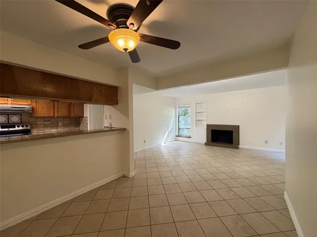 a view of kitchen and empty room with fireplace