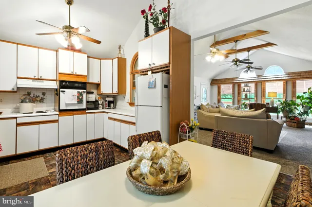 a kitchen with stainless steel appliances kitchen island granite countertop a refrigerator a sink dishwasher a dining table and chairs with wooden floor