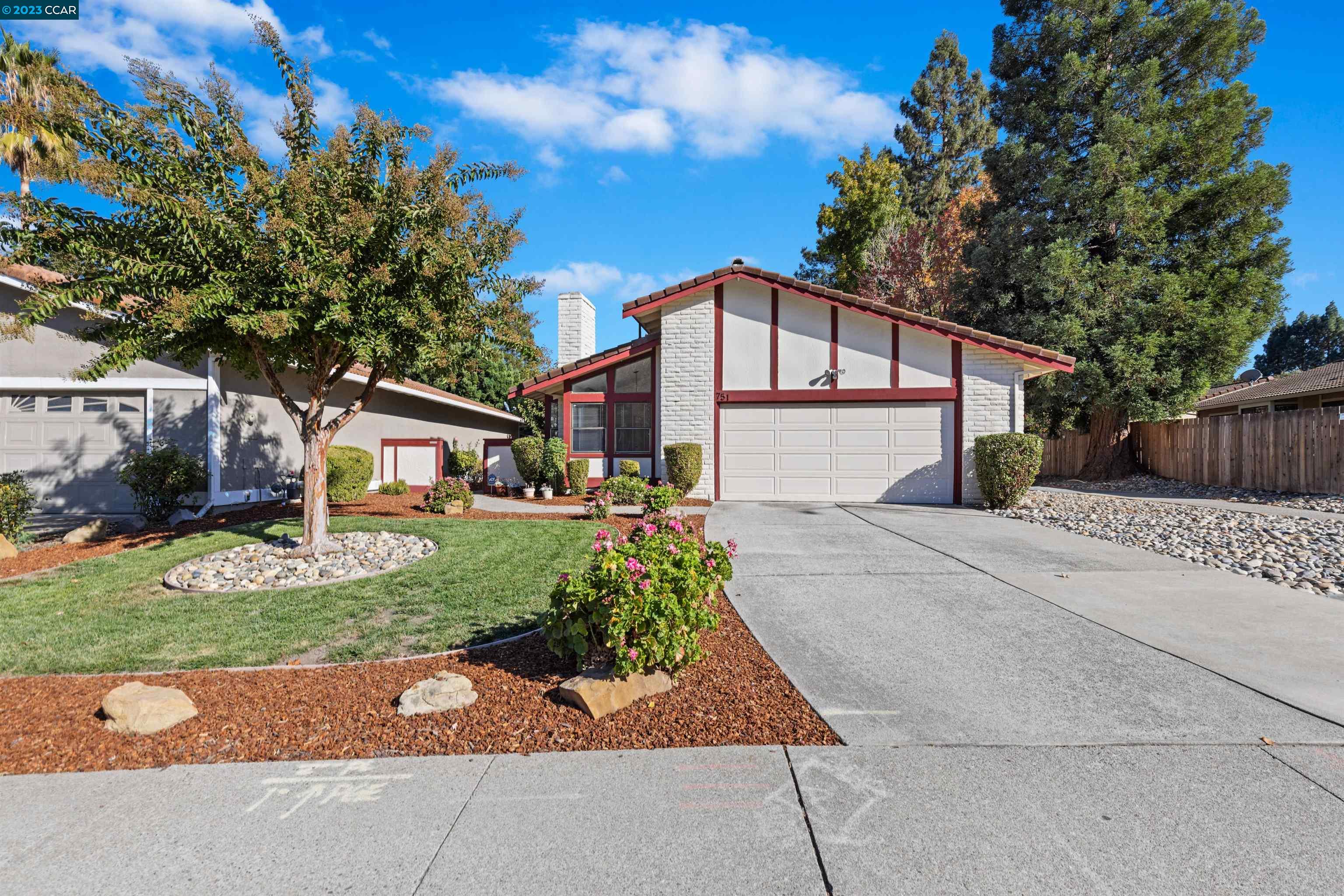 a front view of a house with a garden and trees