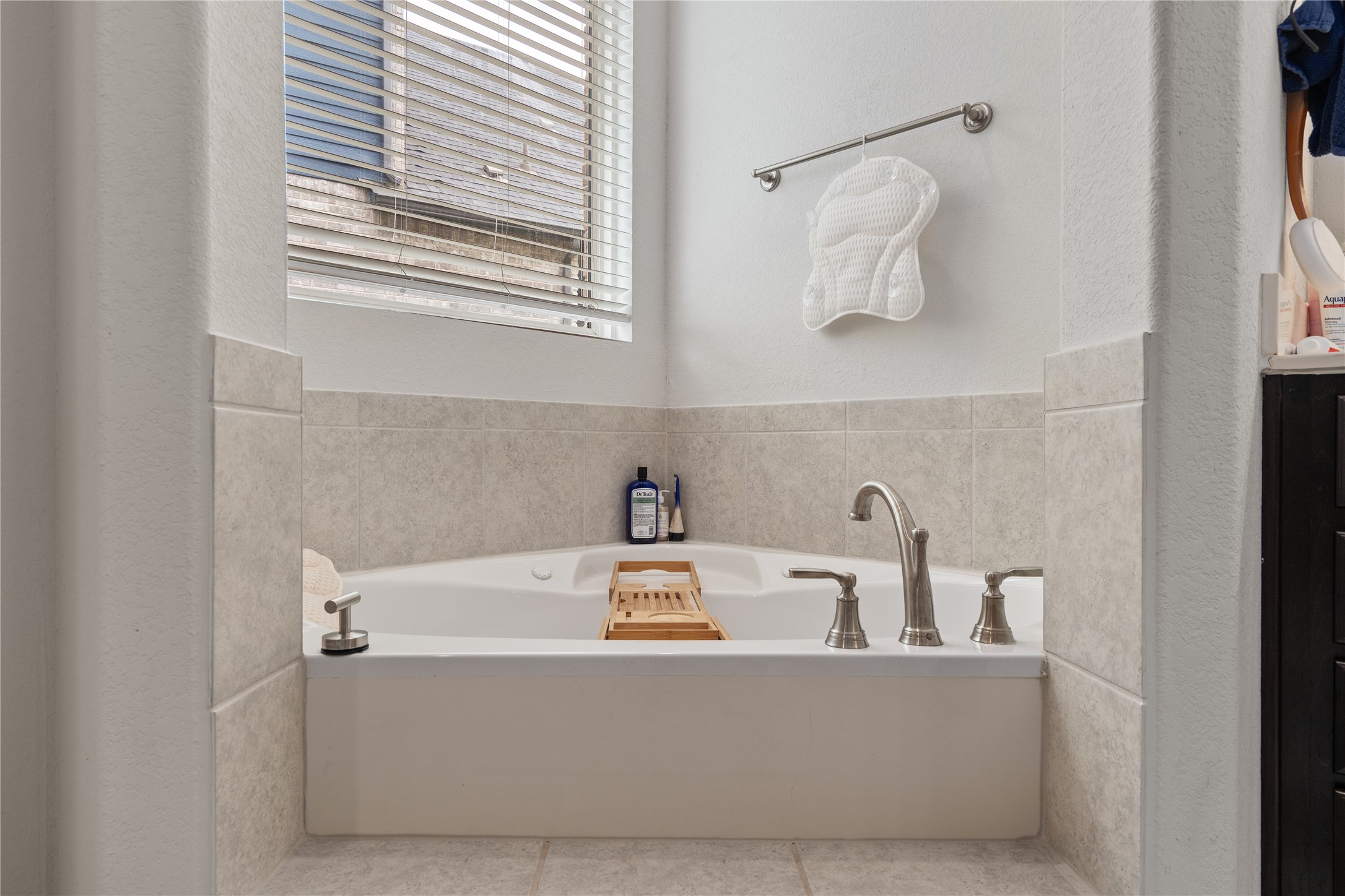130 Wild Pecan Loop Buda, TX 78610 - Photo 16 of 31 Built-in corner soaking tub featuring neutral-toned tile surround and brushed nickel fixtures