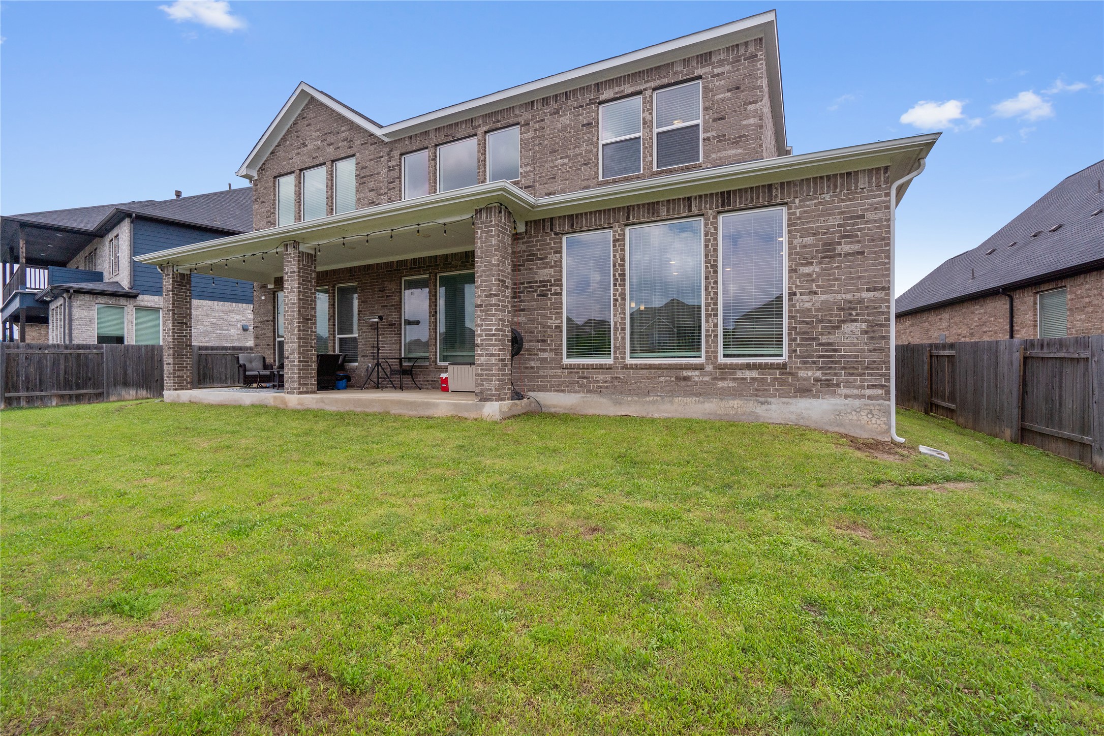 130 Wild Pecan Loop Buda, TX 78610 - Photo 26 of 31 Expansive backyard featuring a covered patio, brick columns, and multiple large windows
