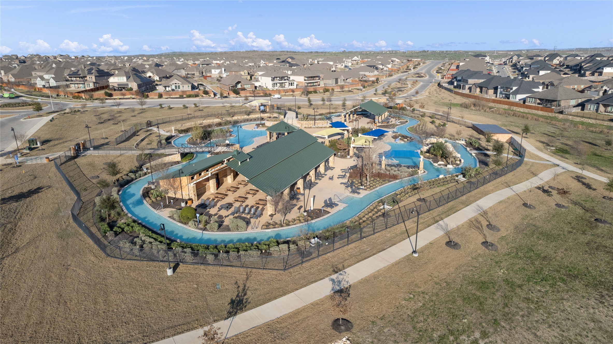 130 Wild Pecan Loop Buda, TX 78610 - Photo 30 of 31 Community recreation area featuring a resort-style swimming pool with a lazy river, water play structures, and shaded lounge areas