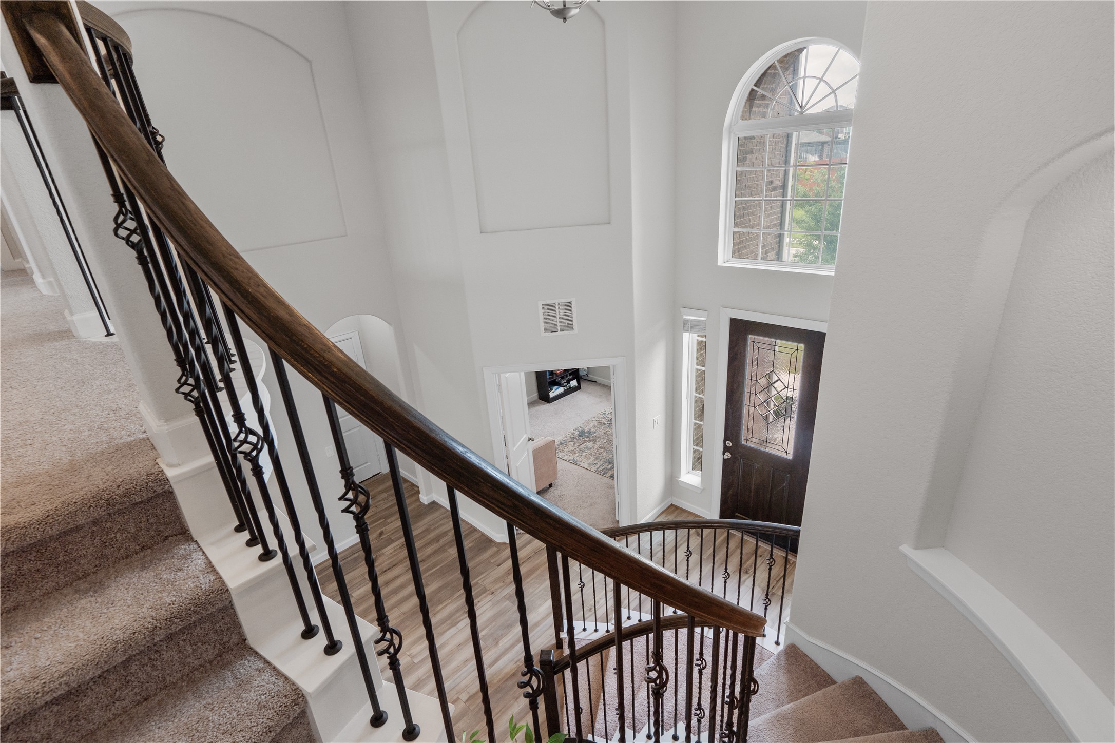 130 Wild Pecan Loop Buda, TX 78610 - Photo 4 of 31 Two-story foyer featuring an arched transom window, dark wood-finish entry door, and curved staircase with wrought iron balusters and a wood handrail