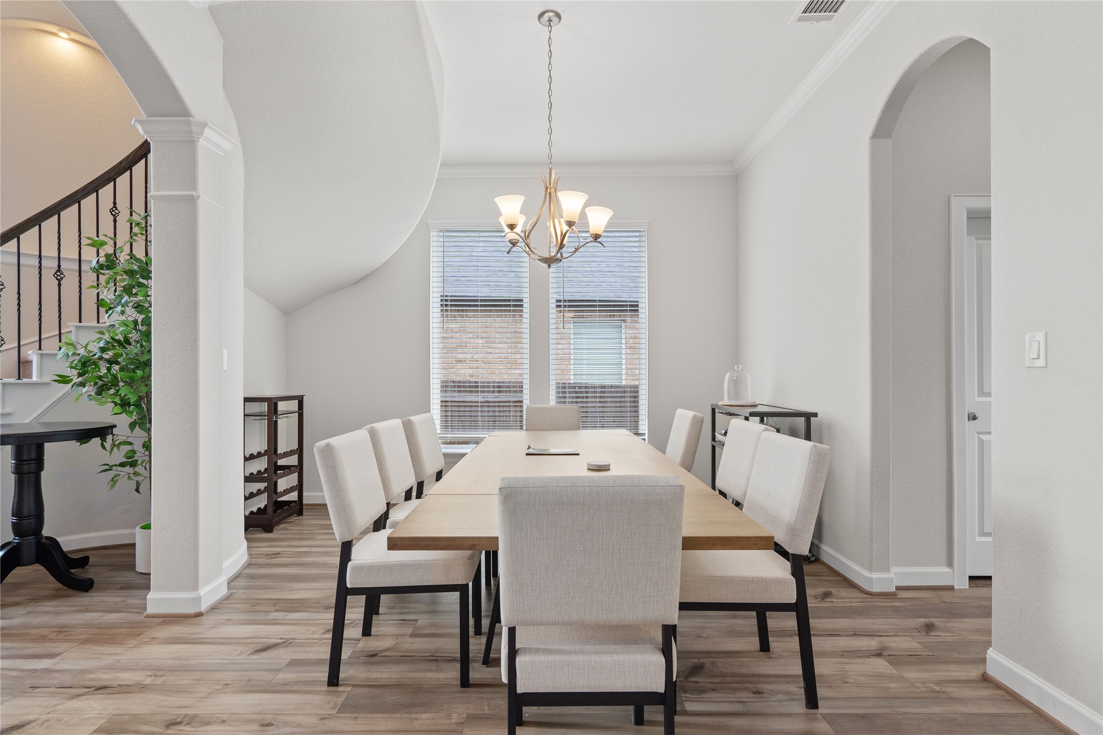 130 Wild Pecan Loop Buda, TX 78610 - Photo 5 of 31 Spacious dining area featuring wood-finish flooring, a contemporary chandelier, a large window with blinds, and an arched doorway
