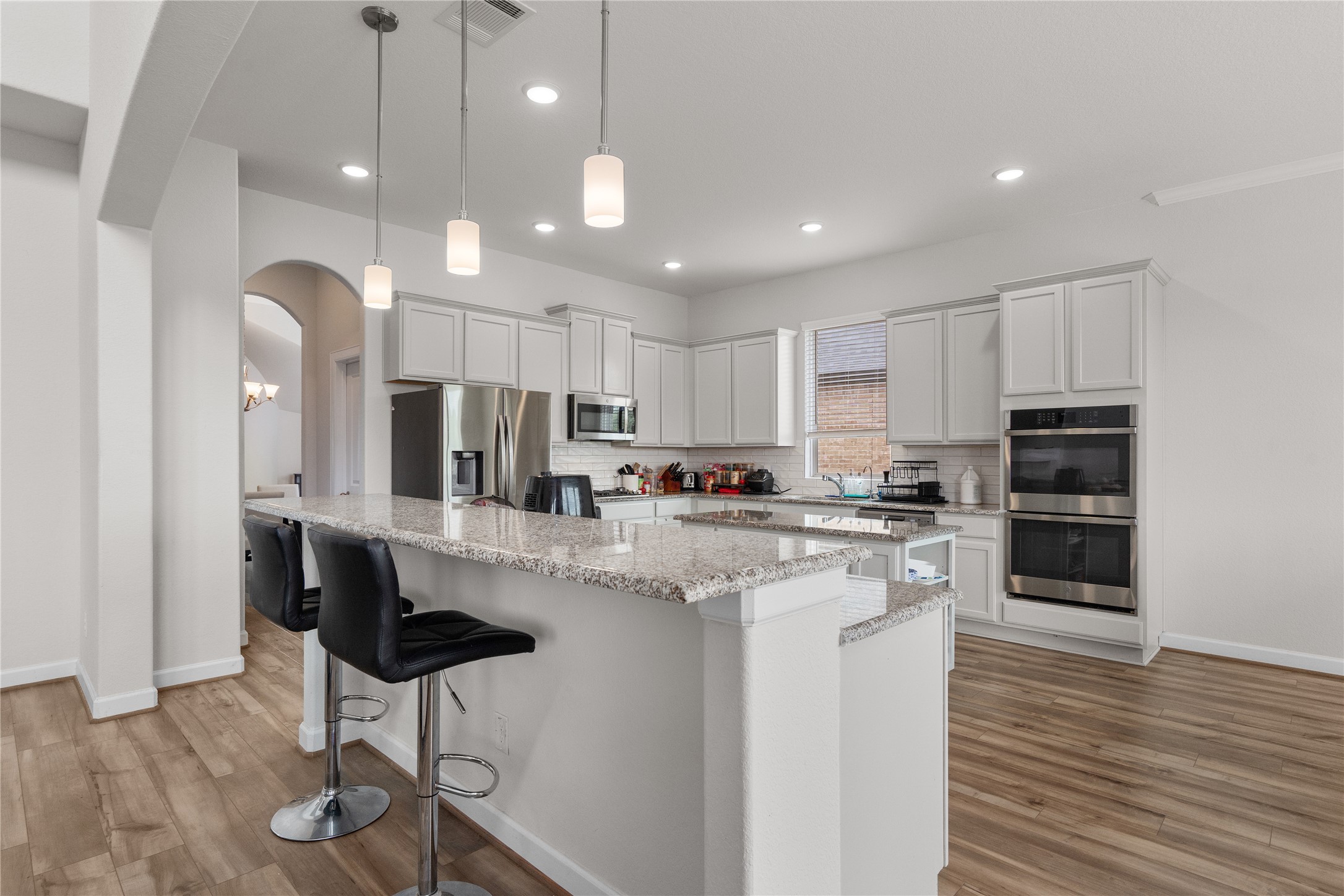 130 Wild Pecan Loop Buda, TX 78610 - Photo 7 of 31 Kitchen featuring wood-finish flooring, white cabinetry, granite countertops, stainless steel appliances, and recessed lighting