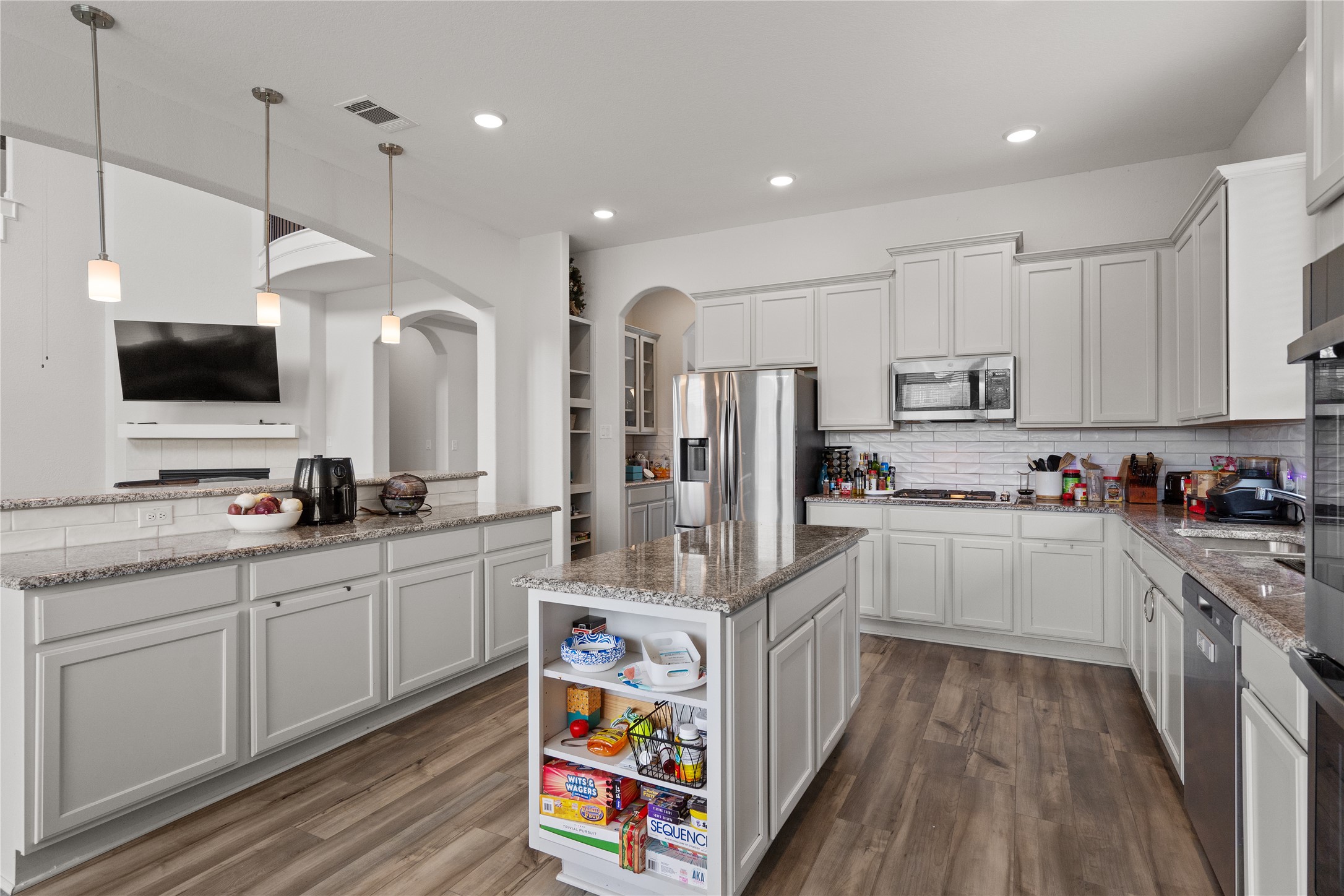130 Wild Pecan Loop Buda, TX 78610 - Photo 8 of 31 Expansive kitchen featuring a central island with integrated shelving, granite countertops, and wood-finish flooring