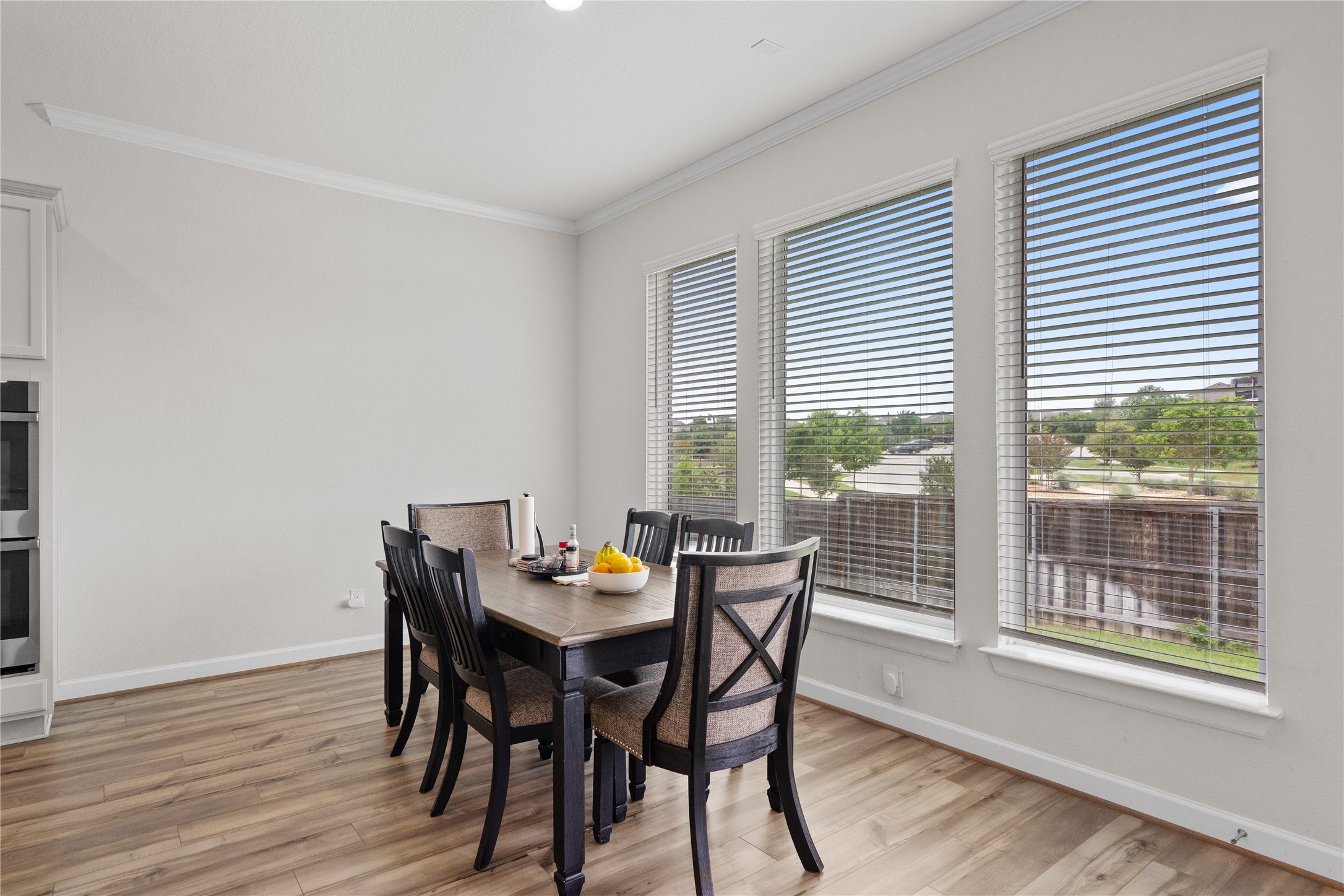 130 Wild Pecan Loop Buda, TX 78610 - Photo 9 of 31 Triple window installation with white blinds, crown molding, wood-finish flooring, and a built-in double oven