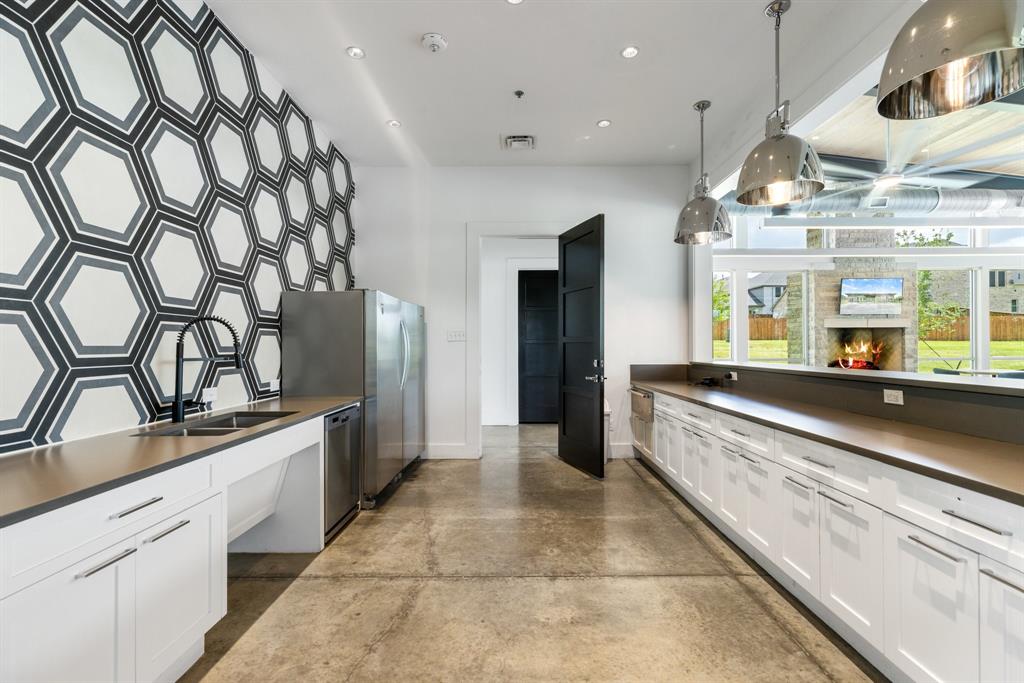 313 Savannah Lane Oak Point, TX 75068 - Photo 32 of 39 Kitchen featuring concrete floors, a lit fireplace, dark countertops, pendant lighting, and white cabinets