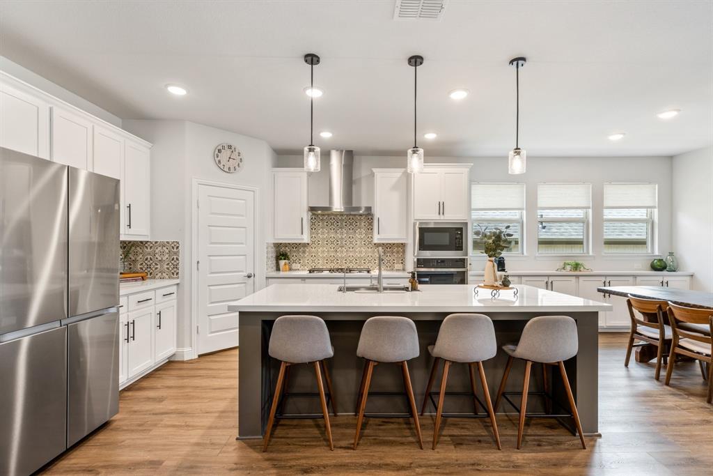 313 Savannah Lane Oak Point, TX 75068 - Photo 4 of 39 Kitchen with stainless steel appliances, white cabinetry, decorative light fixtures, a kitchen island with sink, and recessed lighting